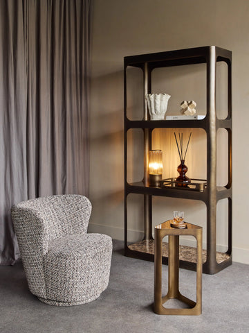 Cozy room with bronze shelving unit, textured chair, and marble accents.