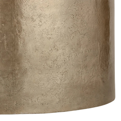 Gold metal surface with textured finish on a drum-shaped table.