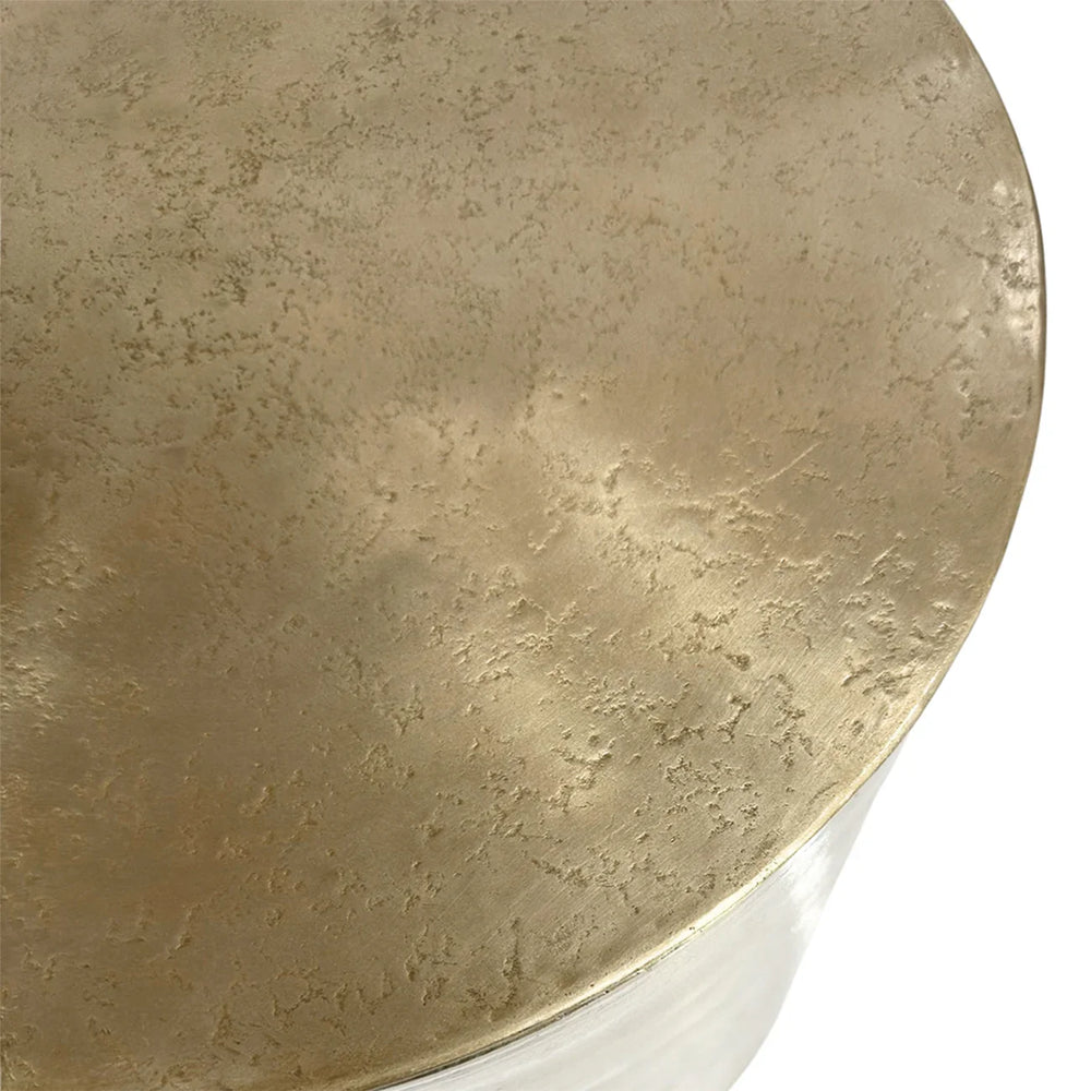Gold metal side table surface with textured finish.