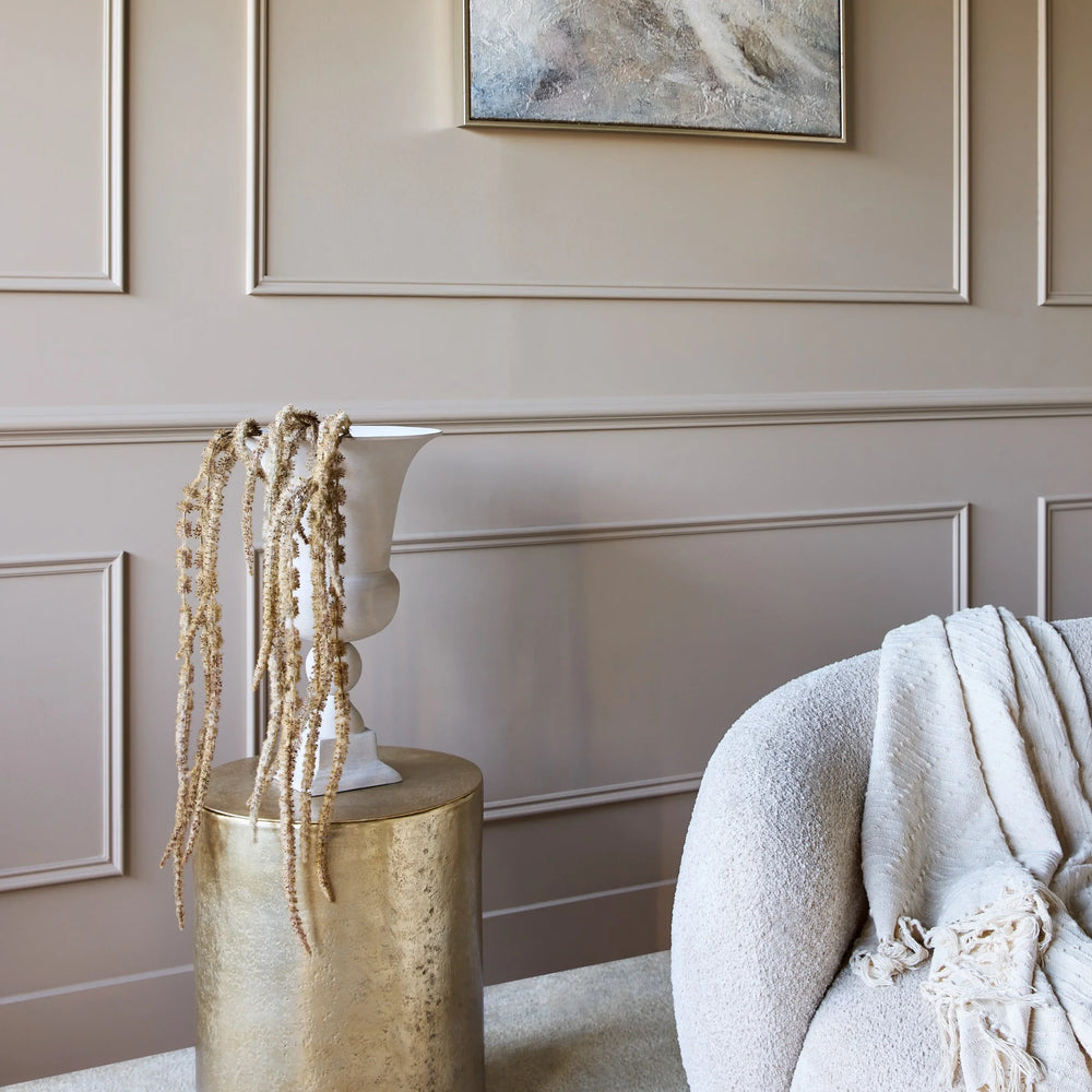 Gold cylindrical table beside a plush sofa in an elegant living room.
