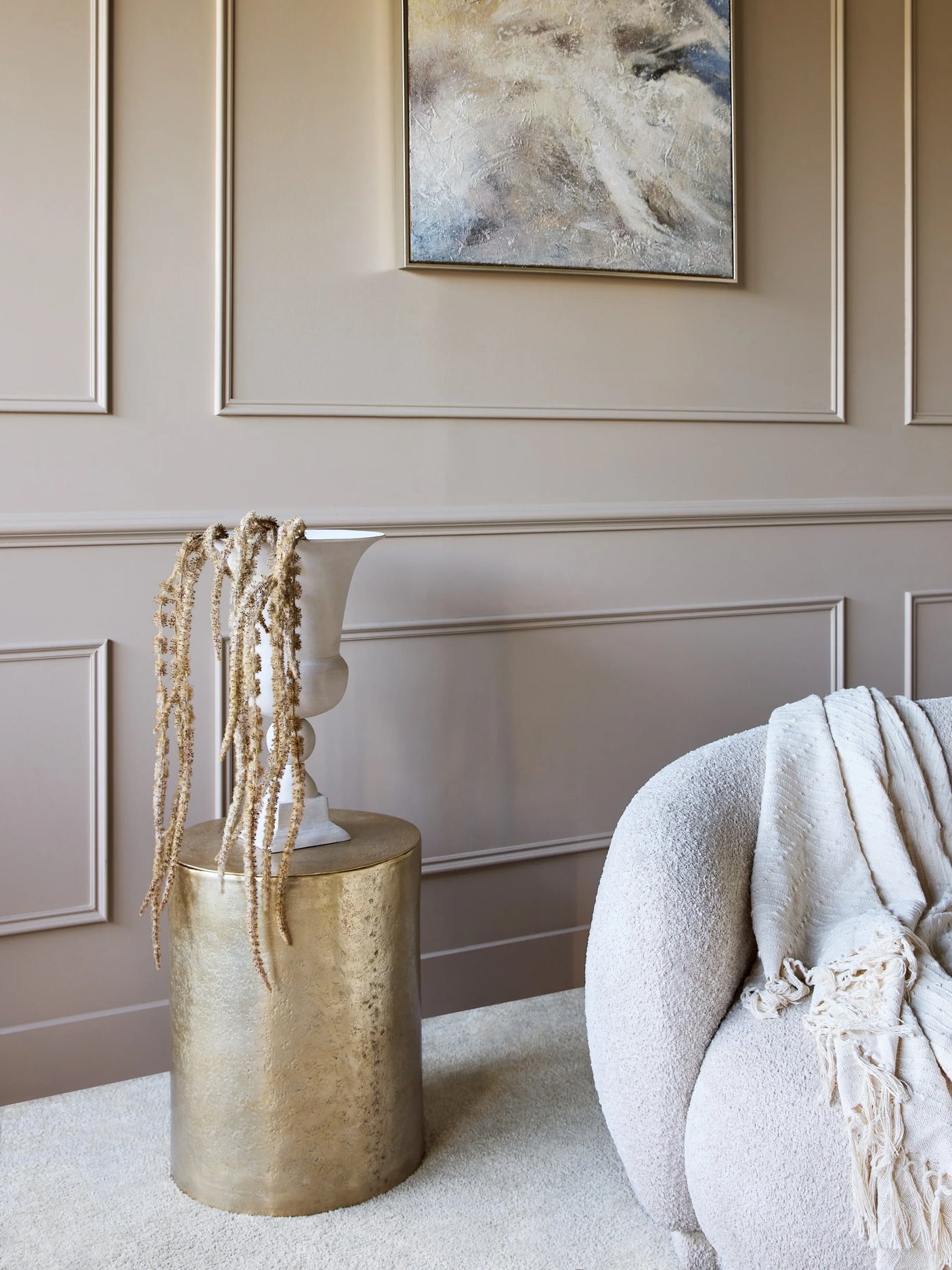 Gold cylindrical table beside a plush sofa in an elegant living room.
