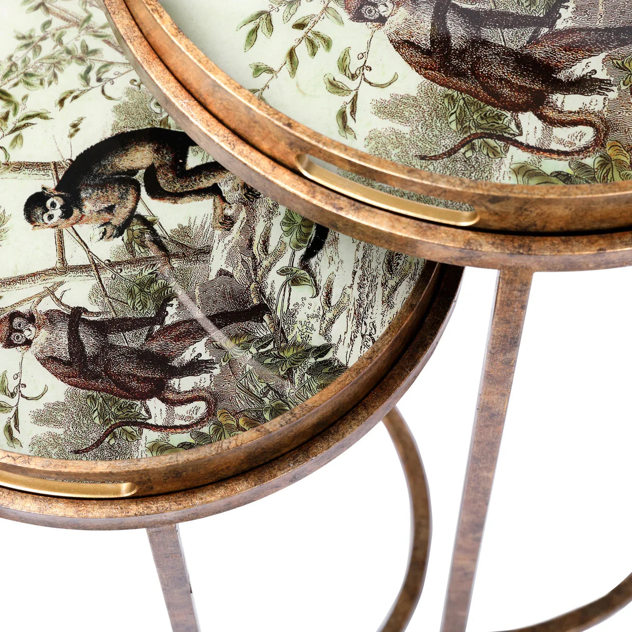 Antique brass tables with jungle monkey illustrations on round trays.
