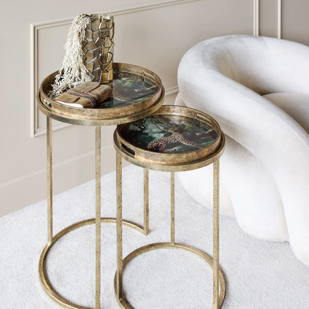 Gold side tables with leopard print tops beside a plush white chair.