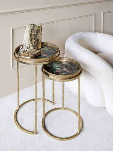 Gold side tables with leopard print tops beside a plush white chair.