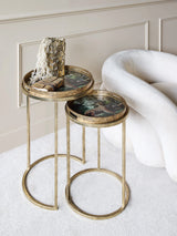 Gold side tables with leopard print tops beside a plush white chair.