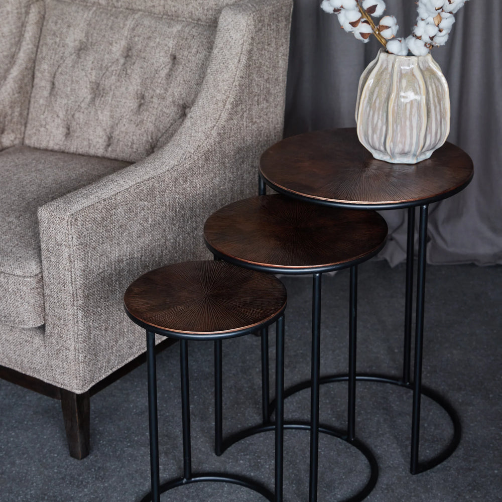 Dark wood and metal nesting tables beside a textured beige armchair.