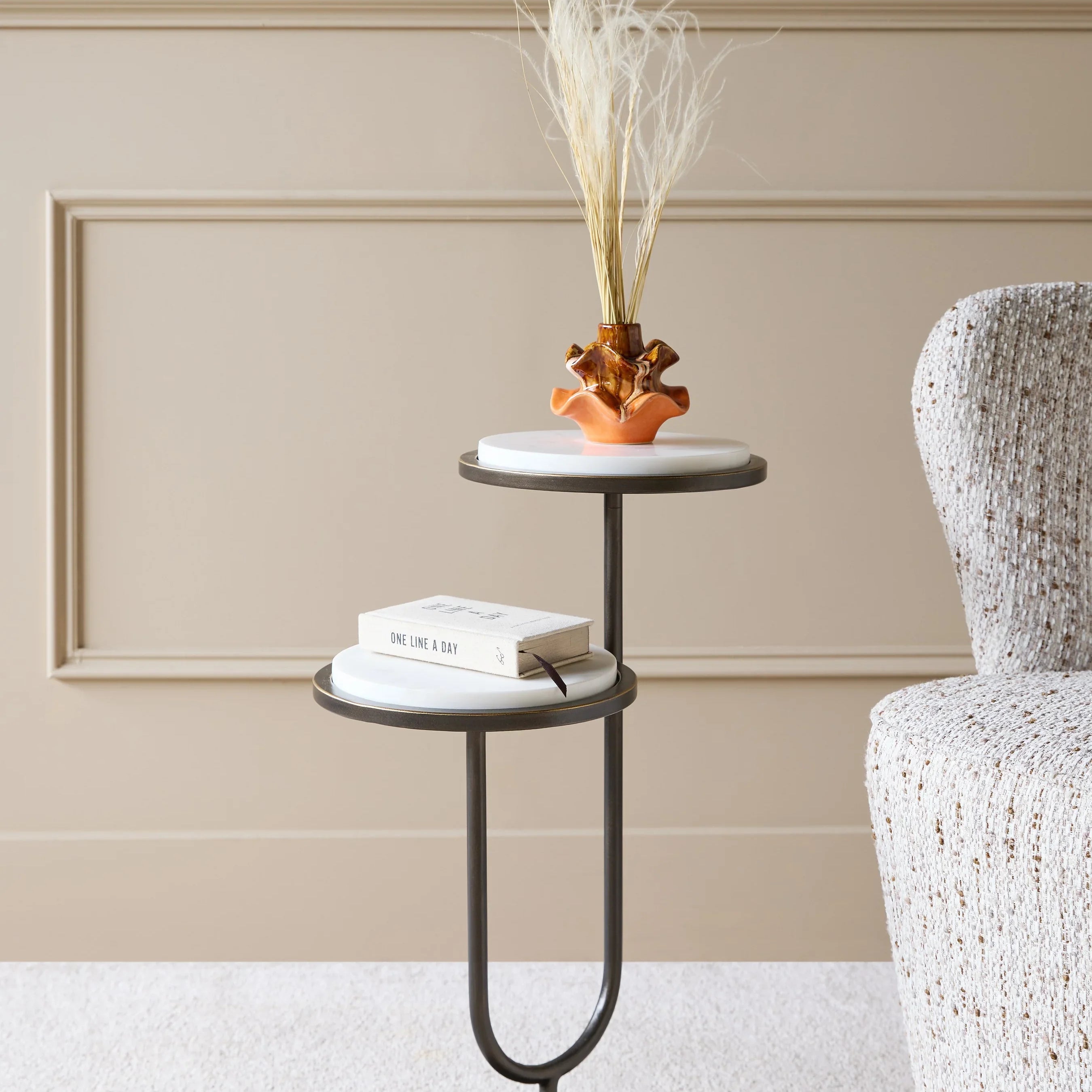 White marble accent table with vase and book in a cozy room setting.