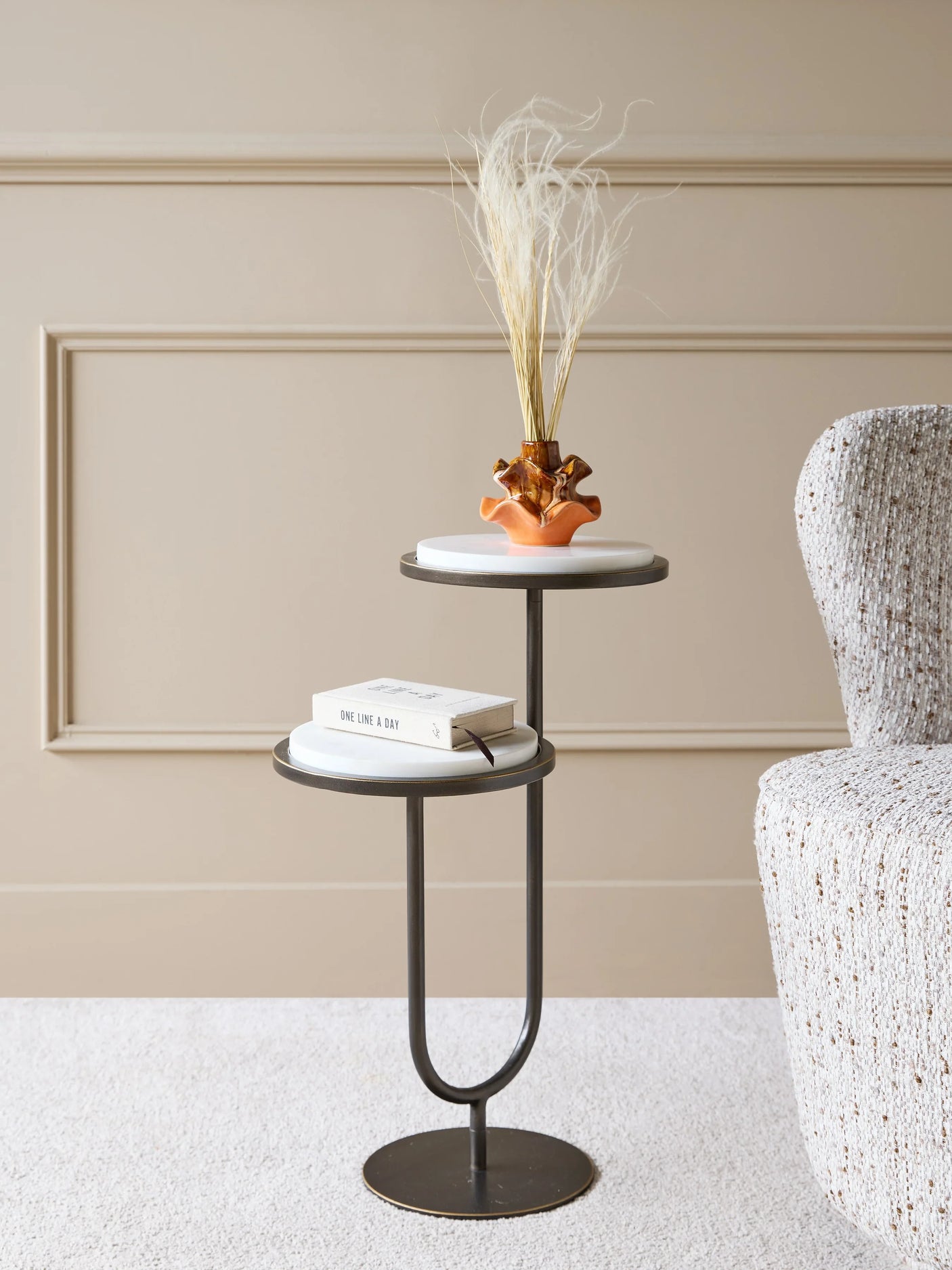 White marble accent table with vase and book in a cozy room setting.