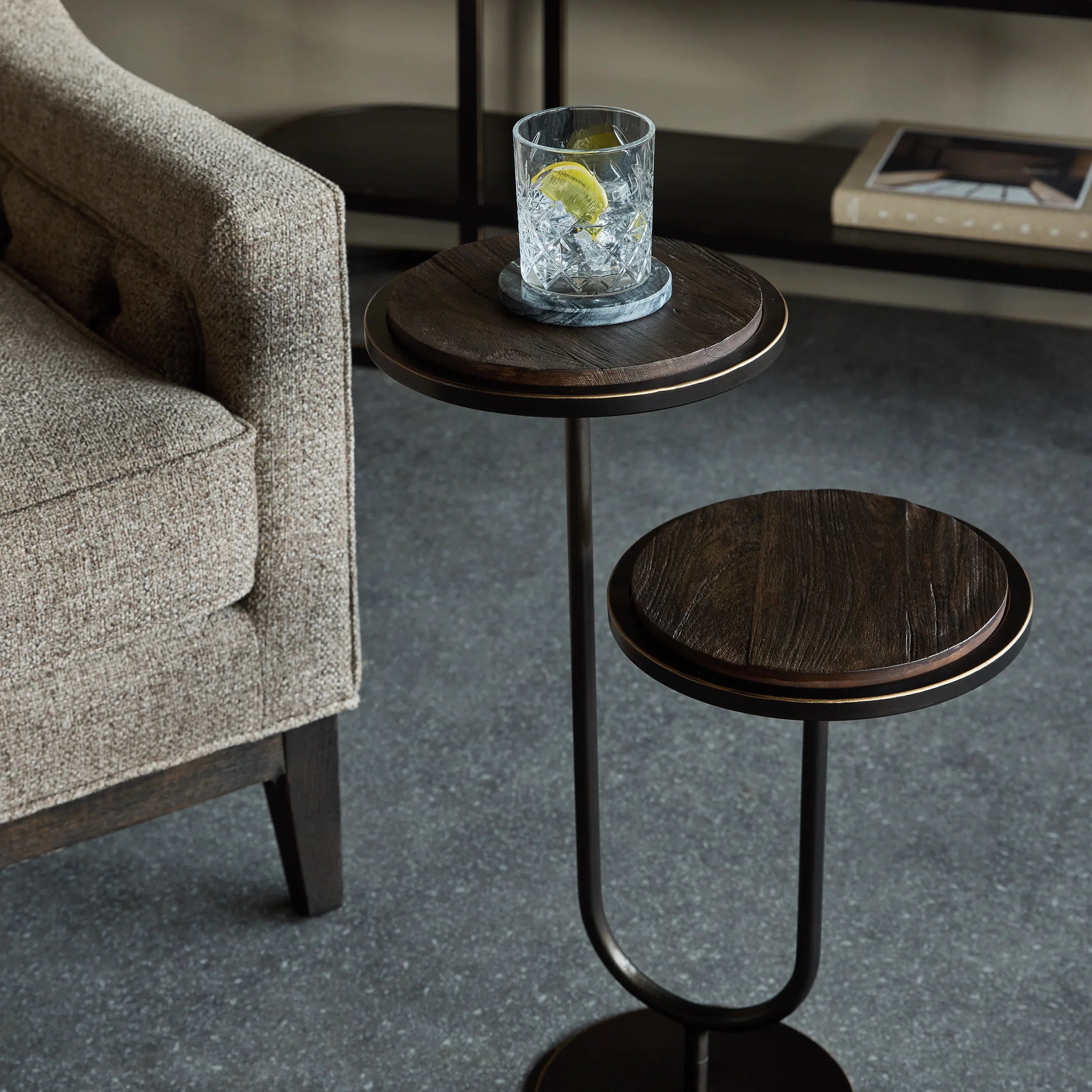 Dark walnut accent table beside beige sofa on grey floor.
