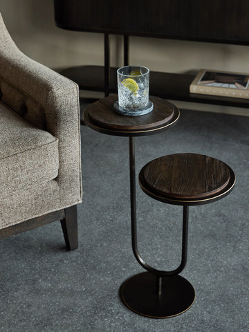 Dark walnut accent table beside beige sofa on grey floor.