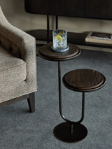 Dark walnut accent table beside beige sofa on grey floor.