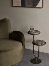 Dark marble accent table beside olive green chair in modern living room.