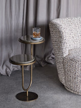 Gold marble accent table with a drink, next to a textured armchair.