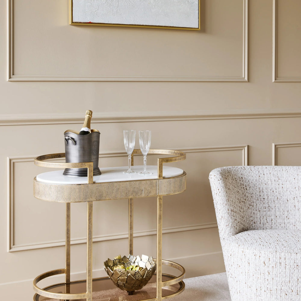 Aged gold drinks trolley in elegant living room with champagne and glasses.