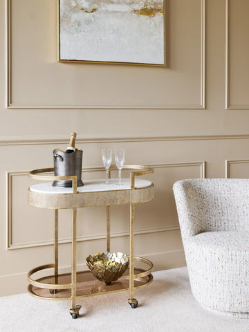 Aged gold drinks trolley in elegant living room with champagne and glasses.