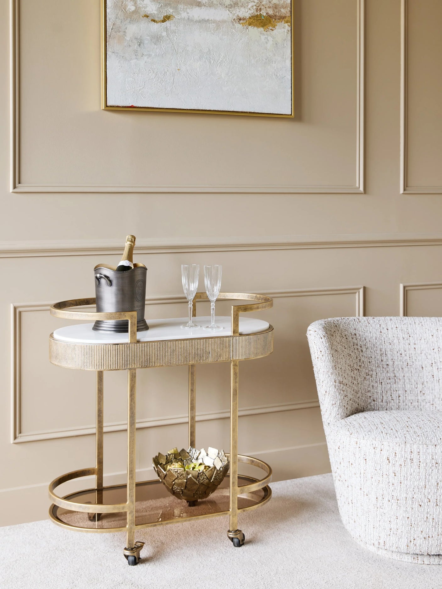 Aged gold drinks trolley in elegant living room with champagne and glasses.