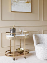 Aged gold drinks trolley in elegant living room with champagne and glasses.