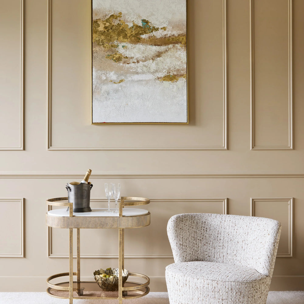 Aged gold drinks trolley beside a textured armchair in an elegant room.