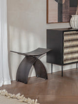Dark iron stool in a modern room with wooden flooring and abstract artwork.