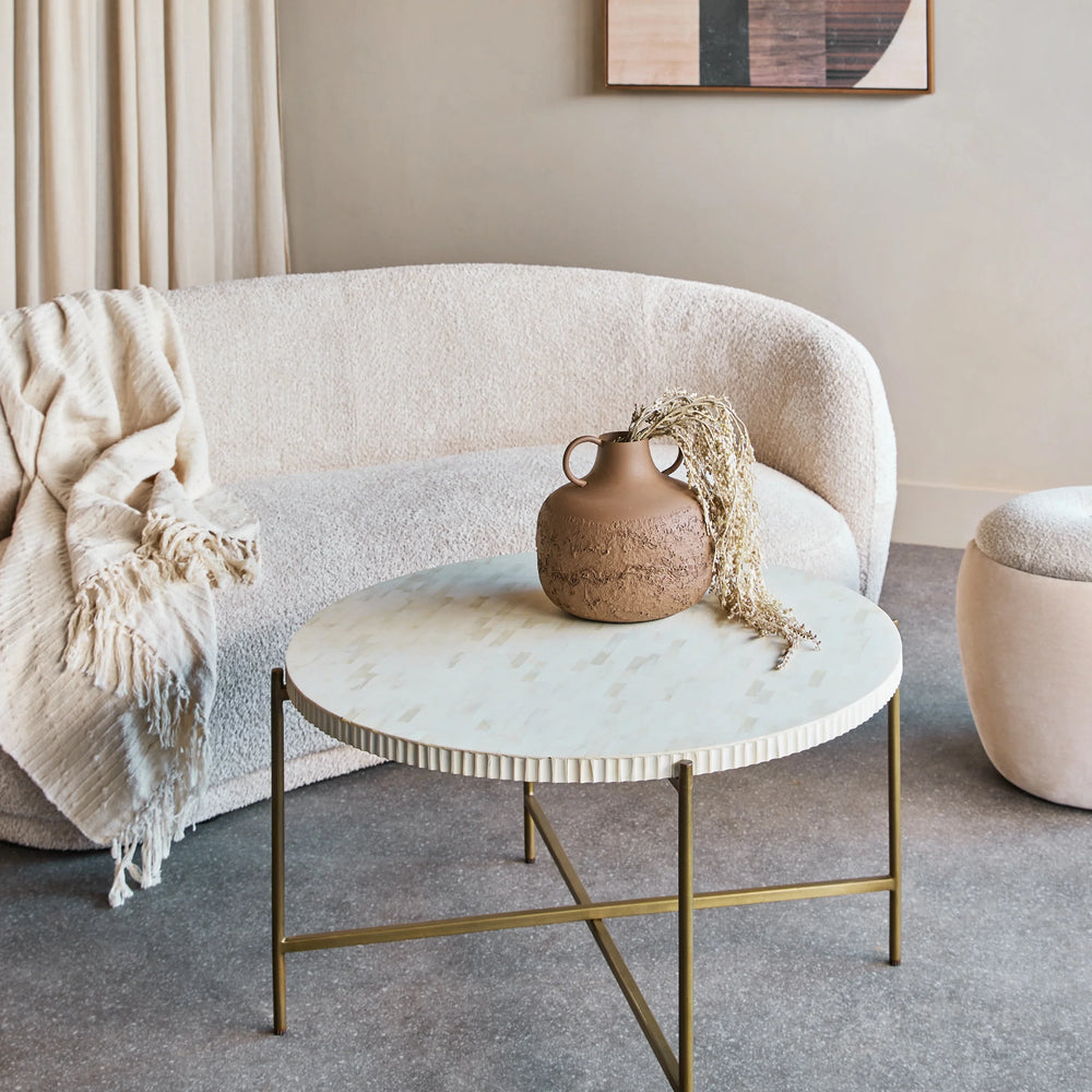 Round bone inlay table with brass legs in a cozy living room setting.