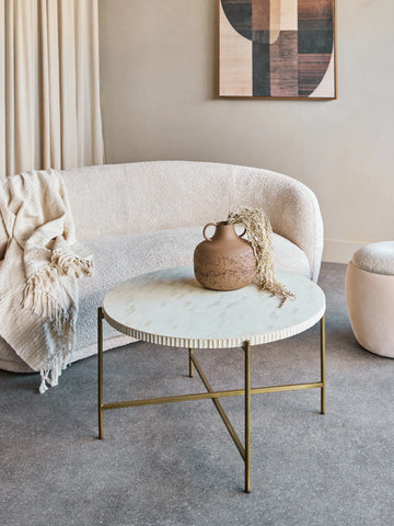 Round bone inlay table with brass legs in a cozy living room setting.