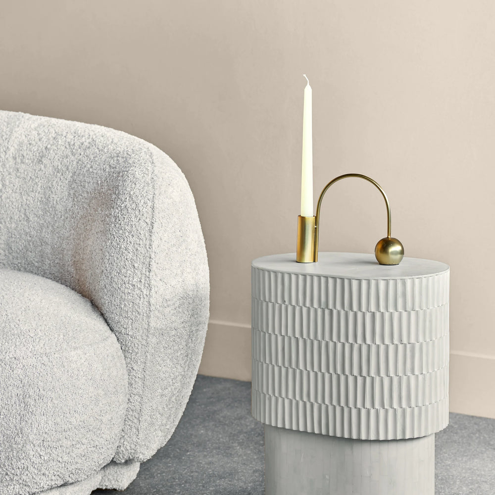 Cream side table with textured inlay beside a plush white chair.