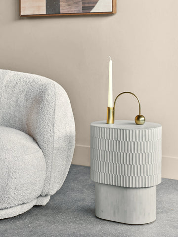 Cream side table with textured inlay beside a plush white chair.