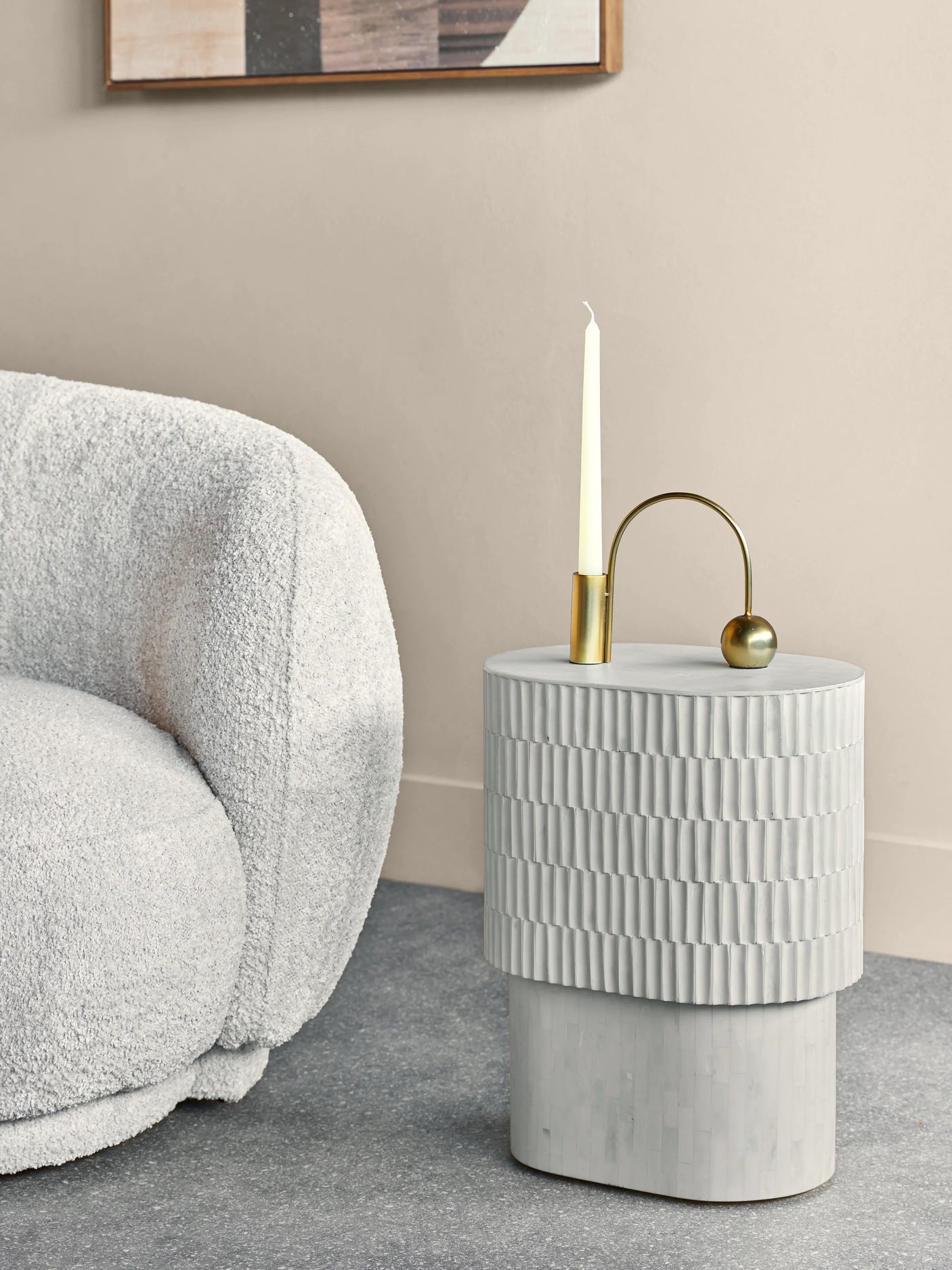 Cream side table with textured inlay beside a plush white chair.