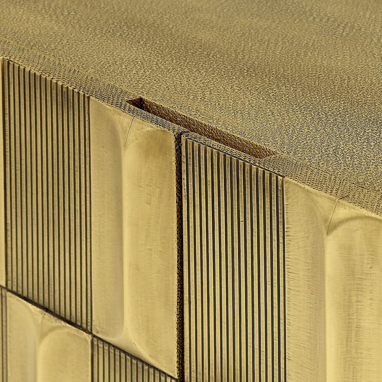 Brass sideboard corner with textured vertical grooves and smooth top surface.