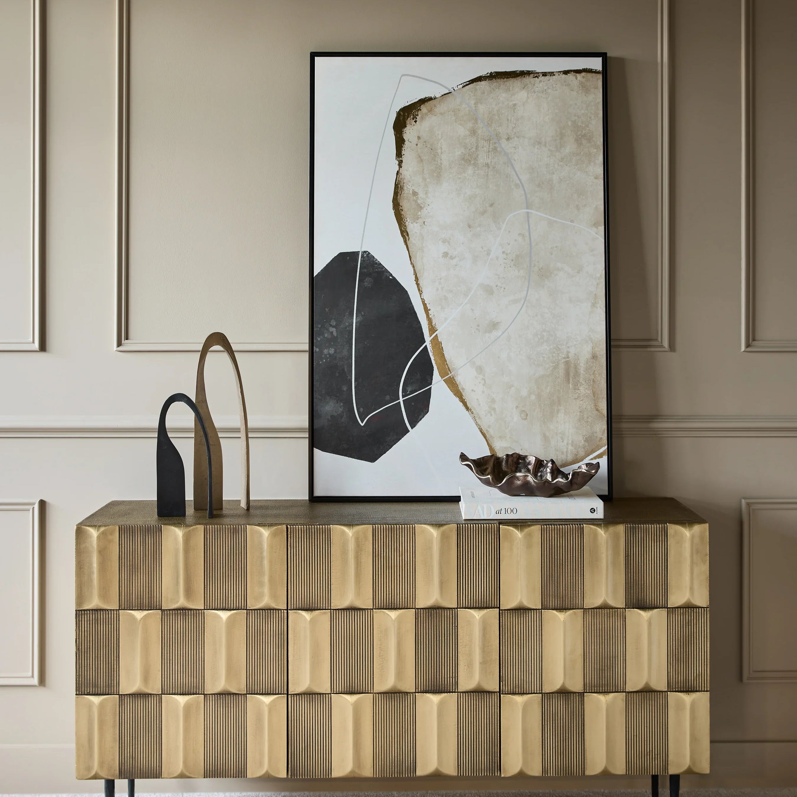 Brass sideboard with textured front, styled with abstract art and decor.