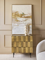 Gold-toned cabinet in elegant room with abstract art and vase.