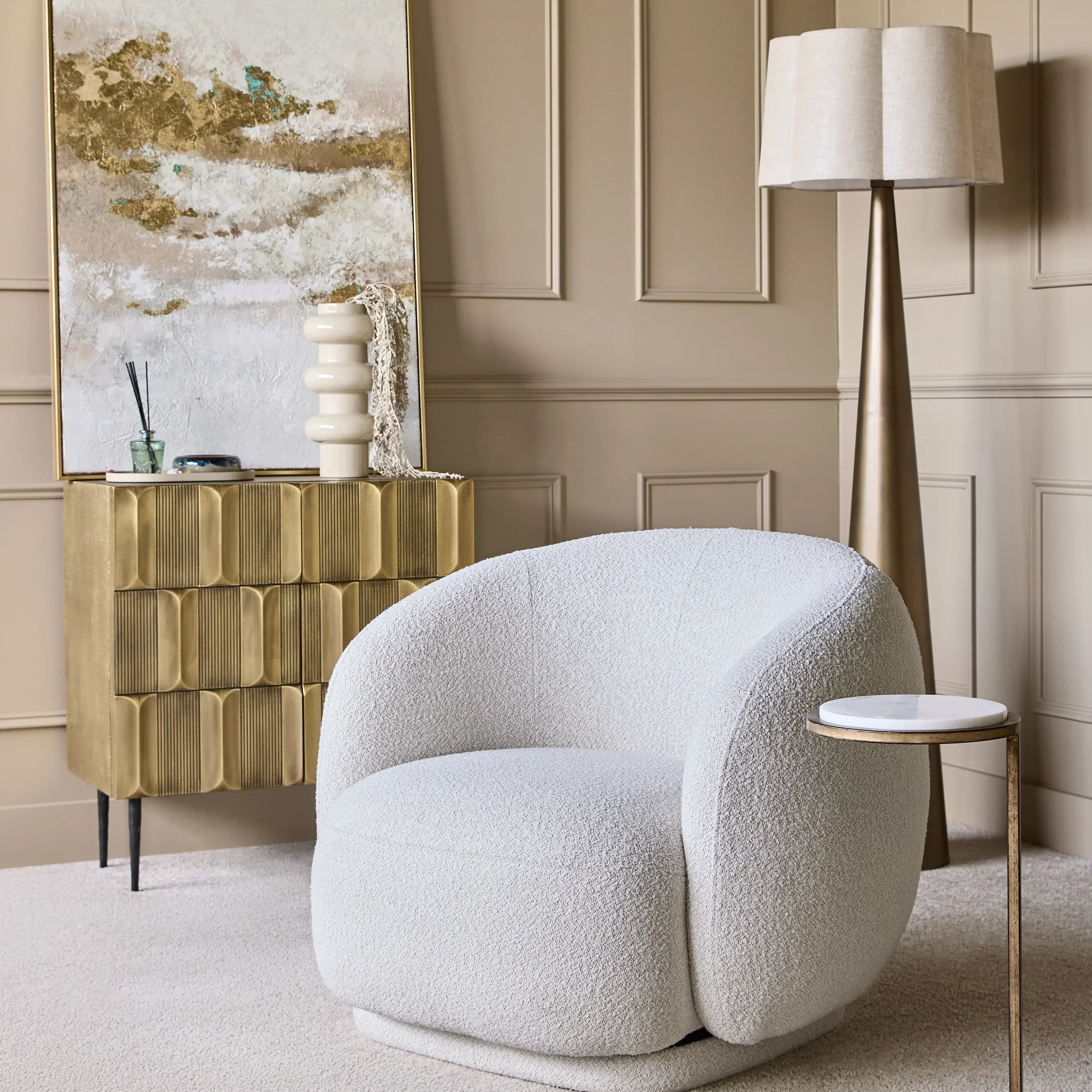 Cozy room with brass cabinet, white armchair, and abstract painting.