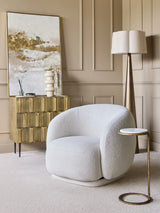 Cozy room with brass cabinet, white armchair, and abstract painting.