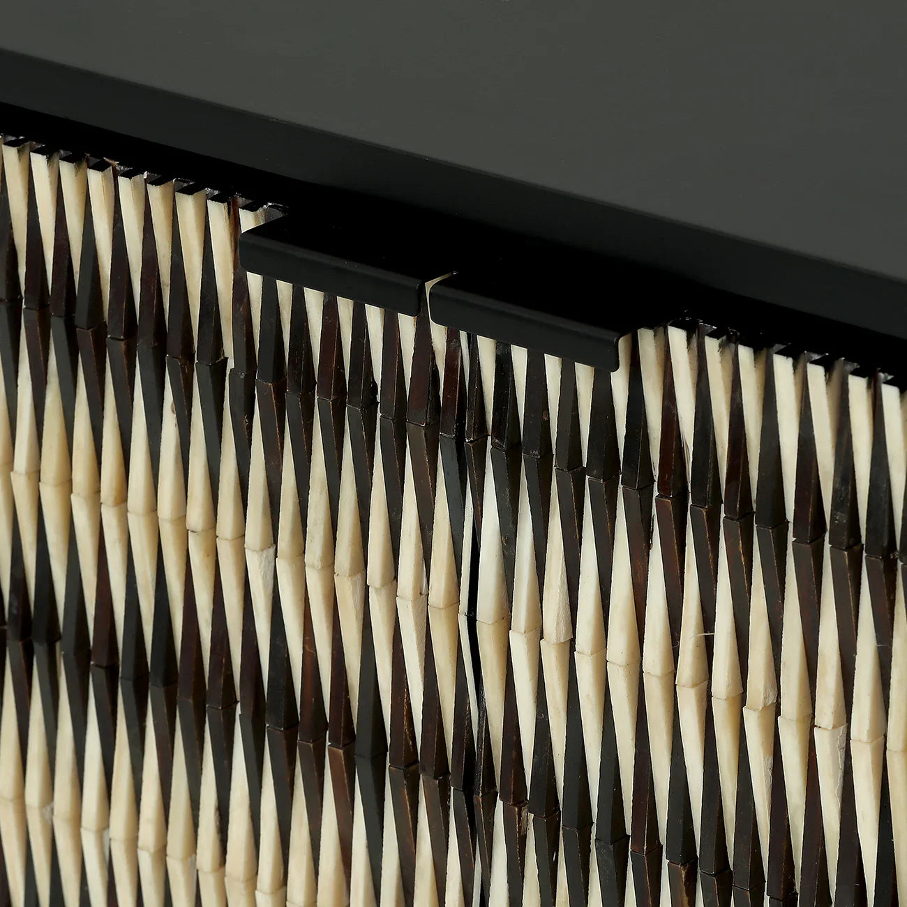Black and ivory sideboard detail with geometric inlay pattern.
