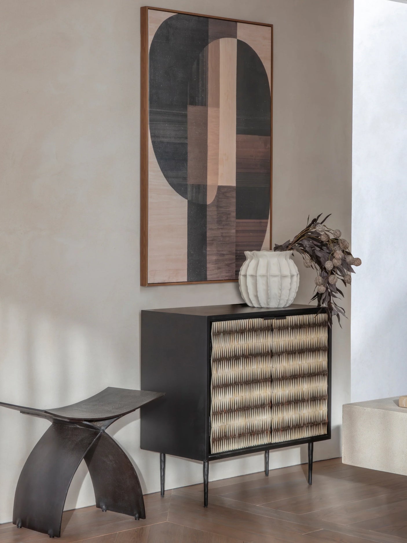 Black cabinet with patterned doors in modern room, abstract art above.