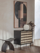 Black cabinet with patterned doors in modern room, abstract art above.