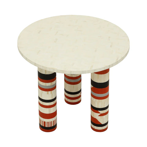 Round bone inlay table with vibrant patterned legs in red, black, and white.