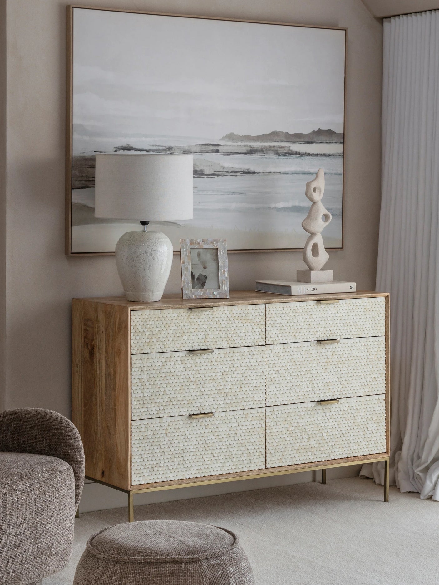 Cream inlay dresser in a serene living room with coastal artwork and decor.