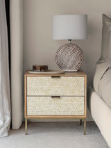 Cream inlay bedside table with textured drawers beside bed and lamp.