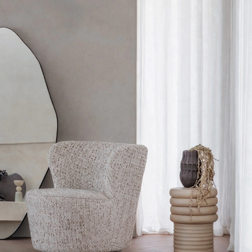Beige ribbed side table with decorative vase in a modern living room.