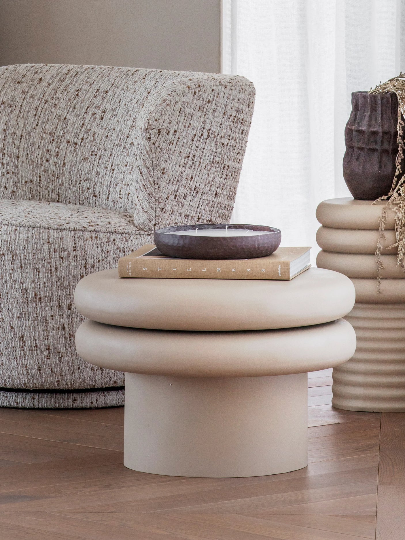 Beige round coffee table with stacked rings, styled in a cozy living room setting.