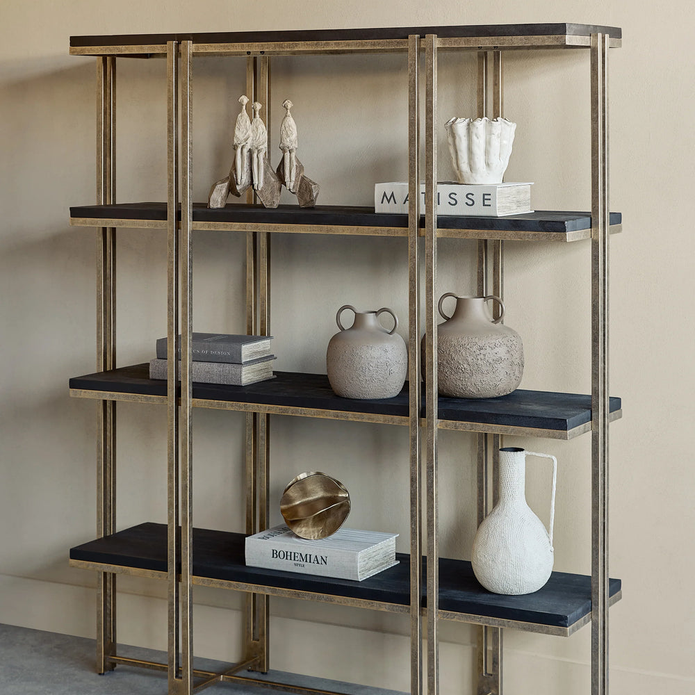 Gold-framed shelving with dark wood shelves, decorated with books and pottery.