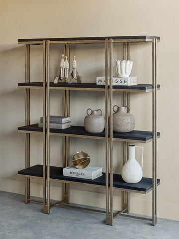 Gold-framed shelving with dark wood shelves, decorated with books and pottery.