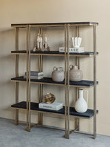 Gold-framed shelving with dark wood shelves, decorated with books and pottery.