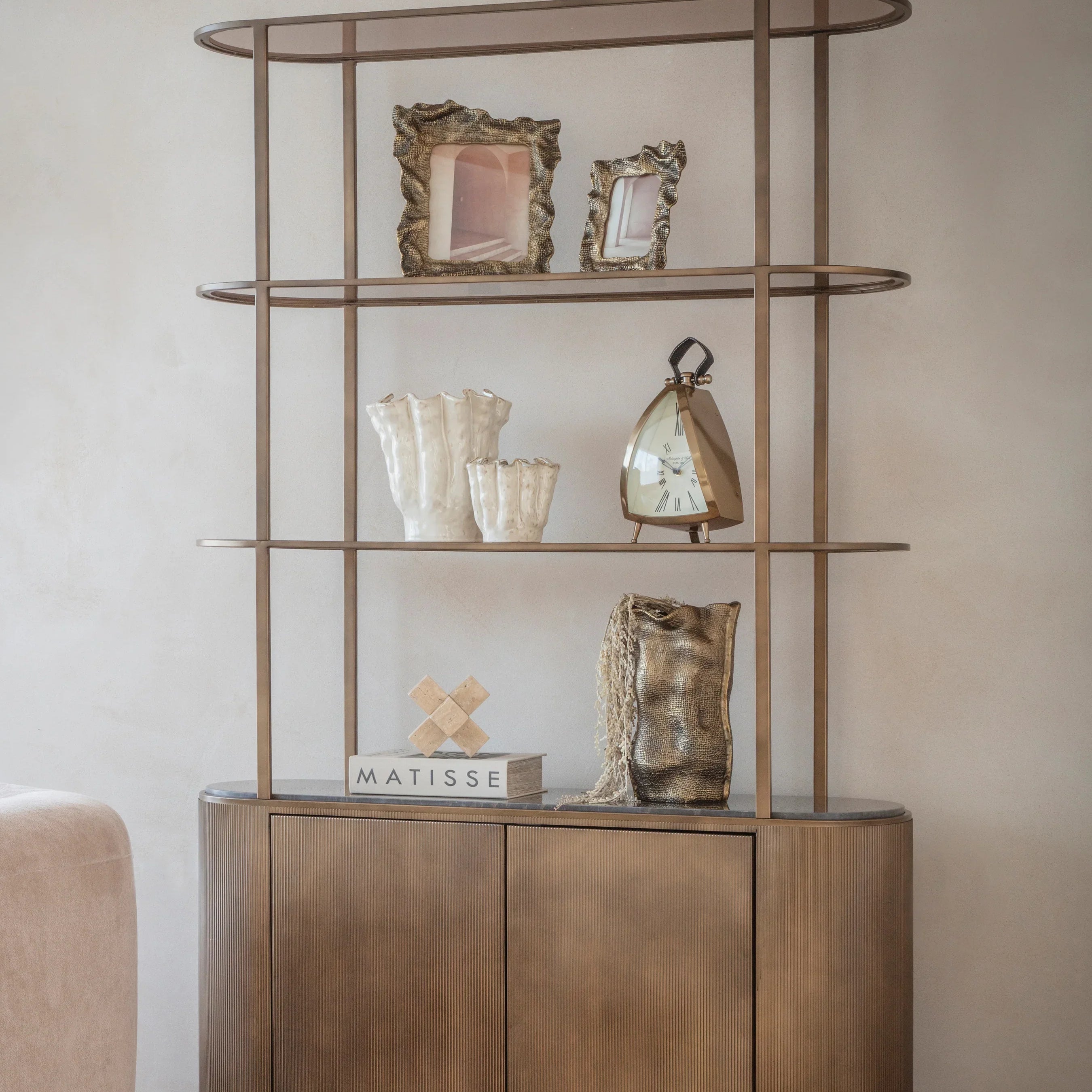Gold shelving unit with decorative items in a modern living room setting.