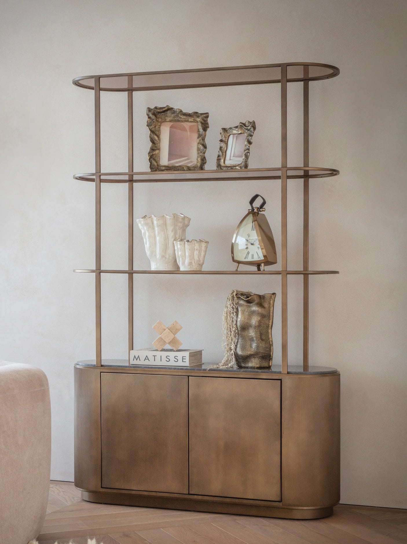 Gold shelving unit with decorative items in a modern living room setting.
