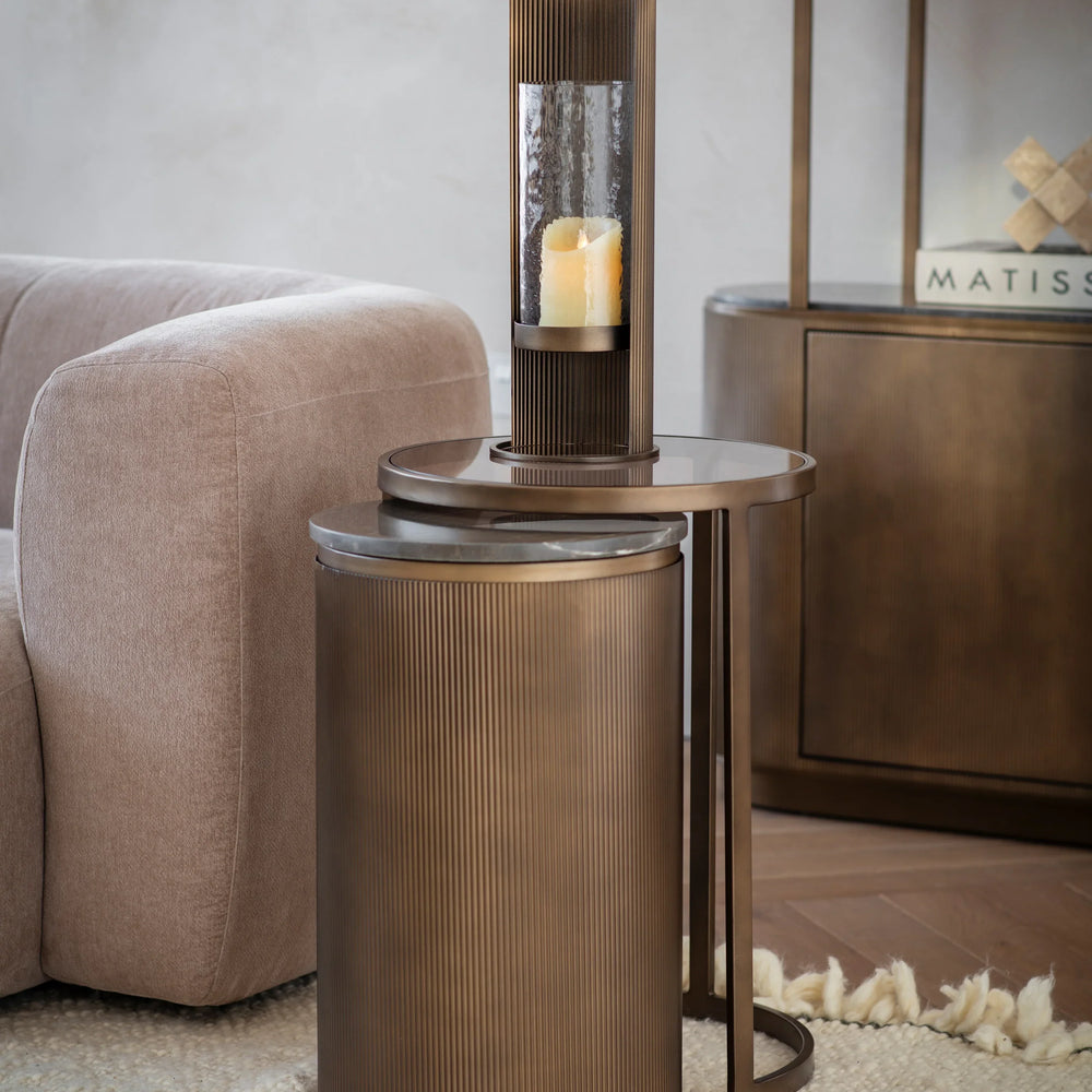 Bronze nesting tables in a cozy living room with a candle and plush sofa.