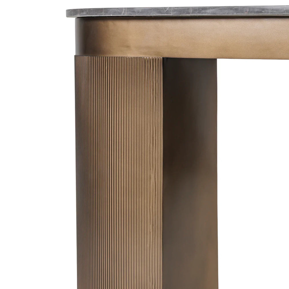 Bronze desk leg with ribbed texture and dark marble top edge.