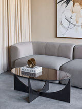 Black sculpted coffee table in modern living room with grey sofa and abstract art.