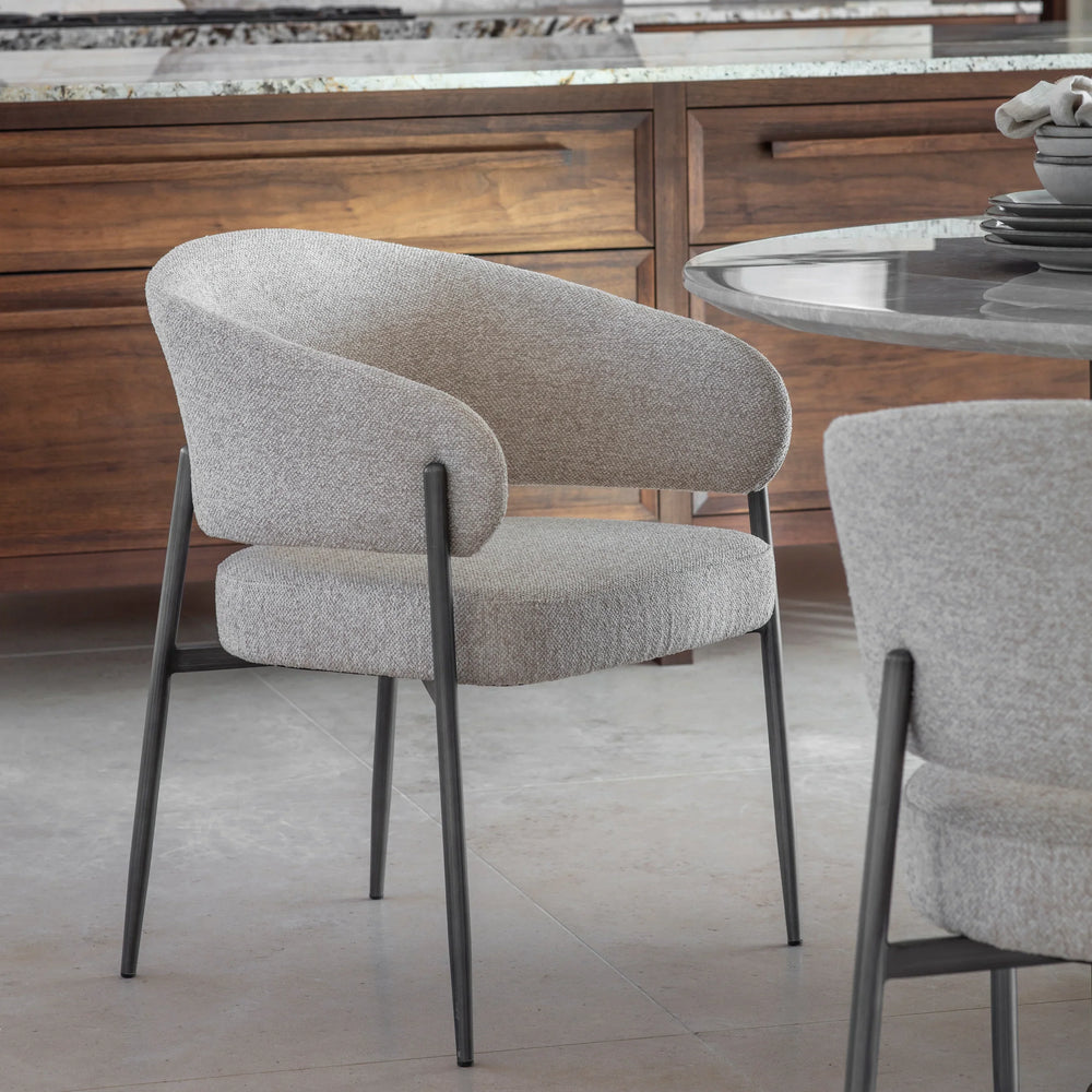 Beige boucle dining chair with black legs in a modern kitchen setting.